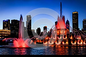 Water fountain in red as the twilight sky turns purple silhouetting the Chicago city skyline