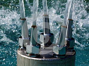 Water fountain stainless steel nozzle closeup with strong water jets. clear fresh water. blue background