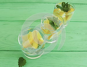 water fresh lemon, mint on a green wooden background
