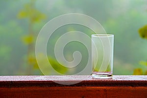 Water glass and flower pot on the wooden deck.