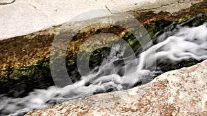 Water gushing out between rocks and flowing