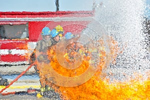 Water hitting fire with firemen