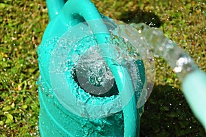 The water hose flows from the garden hose into the watering can. Wasteful wasting water.