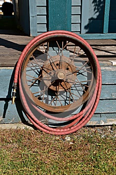 Water hose wrapped around a an old car rim with spokes