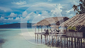 Water Hut of Homestay on Sandy Bank, Clouds in Background - Kri Island. Raja Ampat, Indonesia, West Papua photo