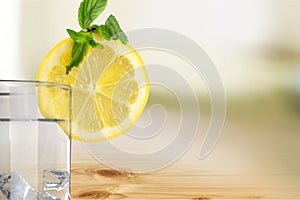 Water with ice and lemon on wooden table