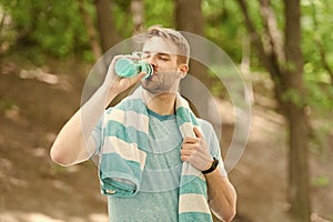 Water is indispensable for human health. Fit athlete having a drink from water bottle during training outdoor. Thirsty