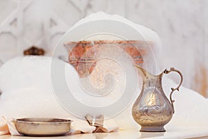 Water jar, towel and copper bowl with soap foam in turkish hamam. Traditional interior details