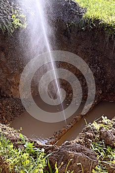 The water jet in the form of leakage in the damaged metal pipe at the production site