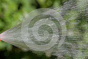 Water jet from a hosepipe with a green background.