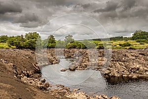 Water of Ken flowing out of a gorge on a drained or dewatered Earlstoun Dam