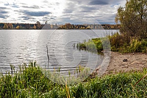 A water landscape with a small sandy beach on an autumn cloudy day