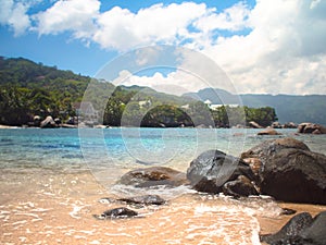 Water lapping against rocks on a Seychelles beach during a sunny