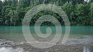 Water laps over shallow gravel beach along aqua river