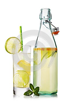 Water with a lemon and a lime in a glass and an open bottle isolated