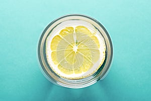 Water with lemon top view close-up on turquoise background