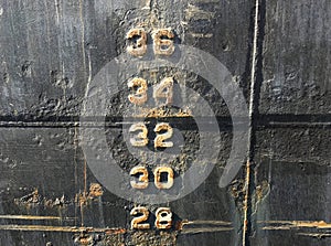 Water level depth gauge number markings on an old black ship hull fragment