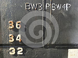 Water level depth gauge number markings on an old black ship hull fragment