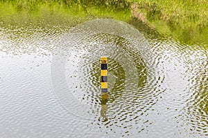 Water level indicator pole in natural lake showing the depth of