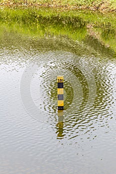 Water level indicator pole in natural lake showing the depth of