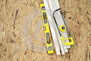 Water level tool, wood material, handsaw and tape lying on the OSB sheet.