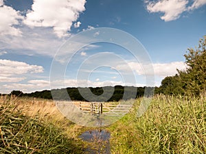 A water logged country walk meadow scene with wooden fence and g