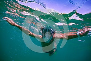 Water lover teenager dive happily among waves in full face mask