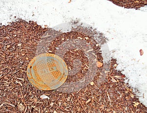 Water Main Cover Next to Melting Snow