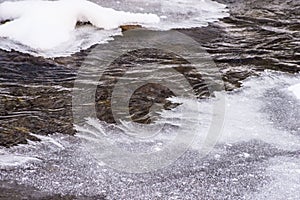 Water makes its way through frozen ice in a small stream.