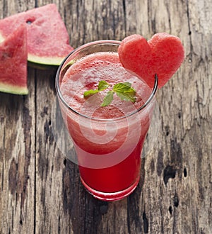 Water melon smoothie and fresh melon on wood background