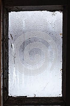 water from melting ice on surface of misted window
