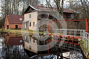 Water mill on the shore of lake and its reflection on the surface of the water