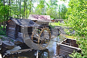 Water mill wheel on river on summer day. Sustainable energy and water power machinery