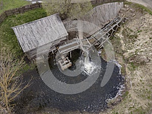 Water mill wheel rotates under a stream of water. Traditional village machinery, aerial view photo