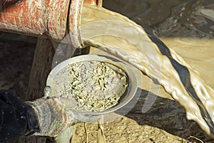 Water mixed with loam from an artificial fountain drilling machine and stones checked with a washing pan