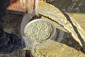 Water mixed with loam from an artificial fountain drilling machine and stones checked with a washing pan