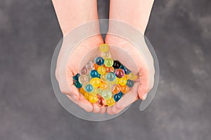 Water multiclooured gel balls. Child palms with hydrogel balls - orbeez.