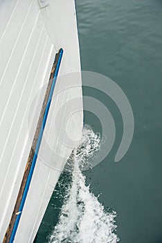 Water passing the bow of a white wooden boat..