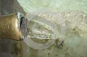 Water permanently flowing from a pipe of a public fountain photo