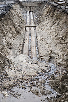 Water pipes in ground during plumbing construction site pit trench ditch