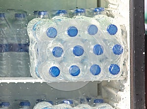 Water in plastic bottles on the shelf in refrigerator.