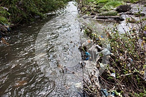 Water pollution. Garbage near the urban stream