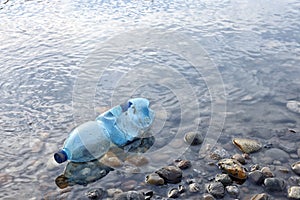 Water pollution. Plastic bottle on the river beach.