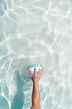 Water polo player with a ball in a blue pool water. Top view. Copy space