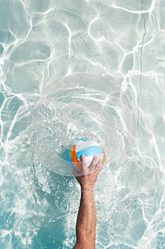 Water polo player with a ball in a blue pool water. Top view. Copy space