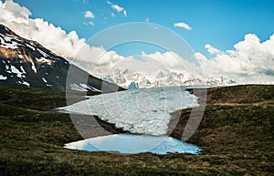 Water pond on the top of the mountain, view on the snowy mountain range.