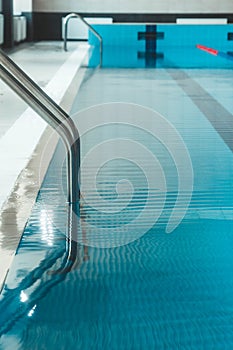 A water pool with blue transparent clear water, on which bright sunlight shines. Water lanes in the swimming pool. indoor sports