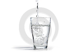 water is poured into a drinking glass, isolated on a white background with copy space