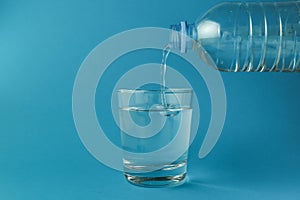 Water is poured into a glass on blue background