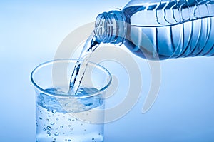 Water poured into the glass. Crystal drink water on light blue background